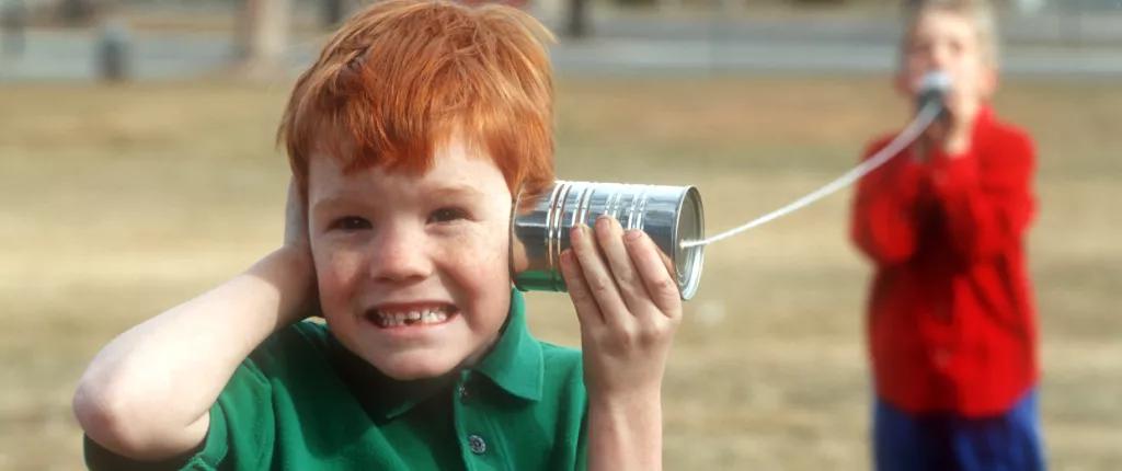 Boy using tin can as telephone
