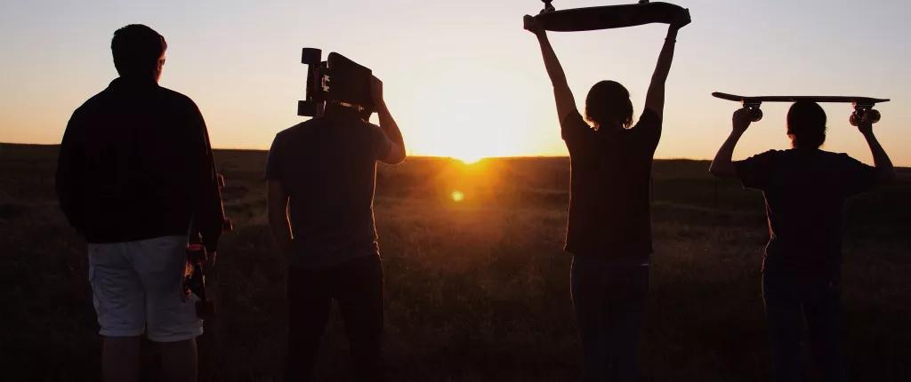 Holding up skateboards to the sunset