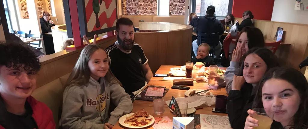 group of teenagers sat around a table at a restaurant
