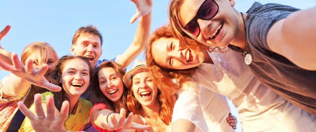 Happy young people waving hands at the camera