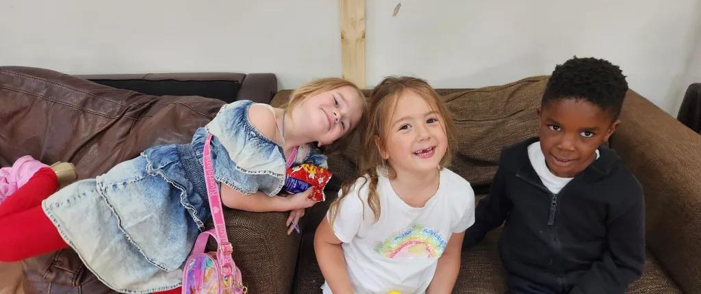 3 young children laughing on sofa