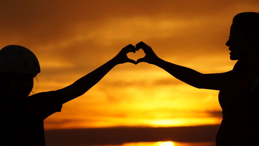 Child and adult in front of a sunset
