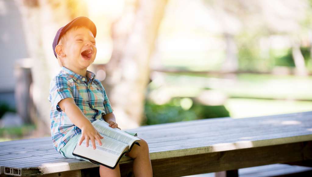 Small boy with Bible laughing