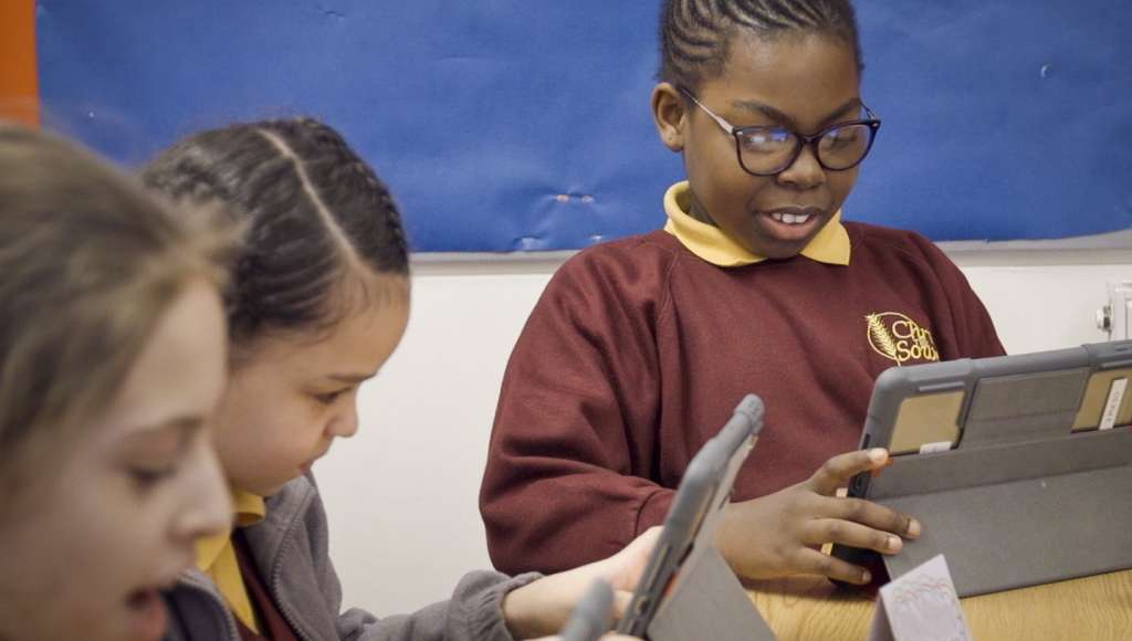 Three girls on computer tablets.