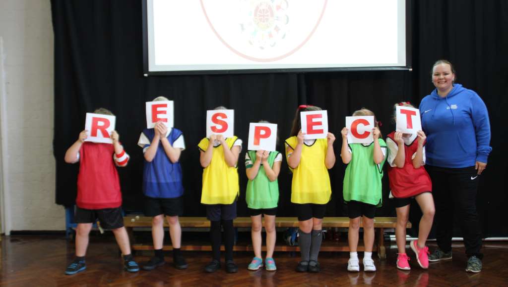 Children holding upon RESPECT signs with Tabz (Faith Guide)