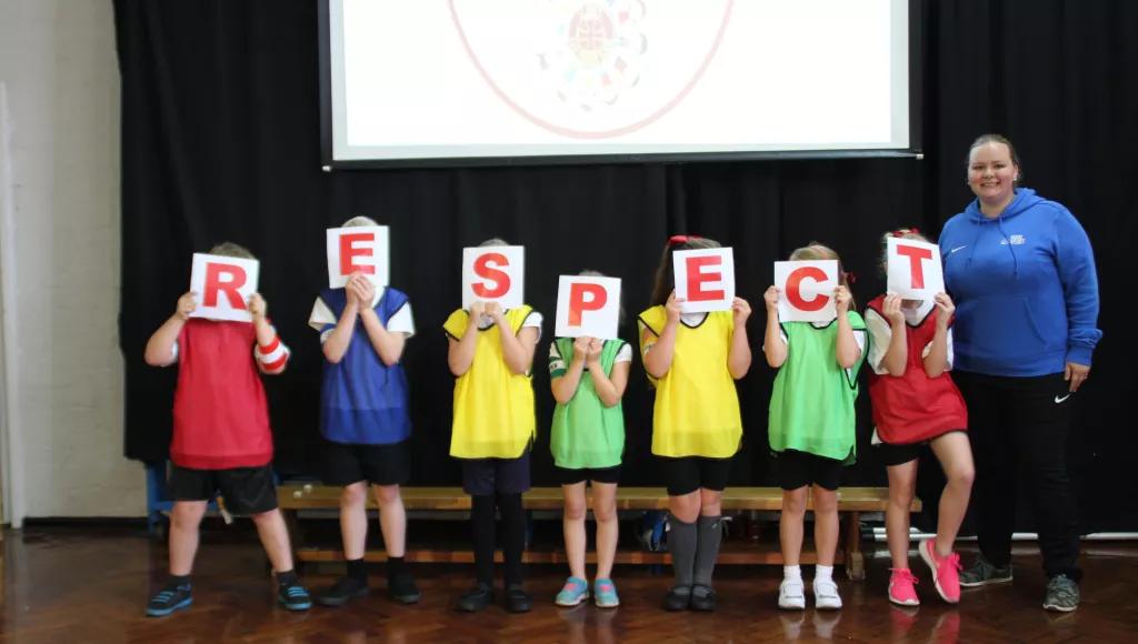 Children holding upon RESPECT signs with Tabz (Faith Guide)