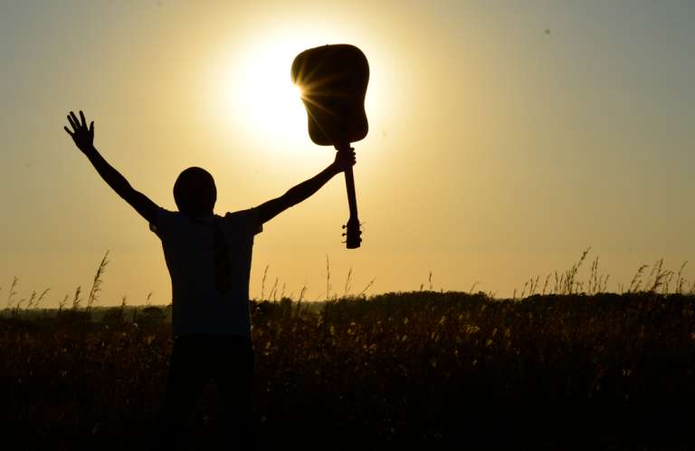 Teenager with his guitar in the air