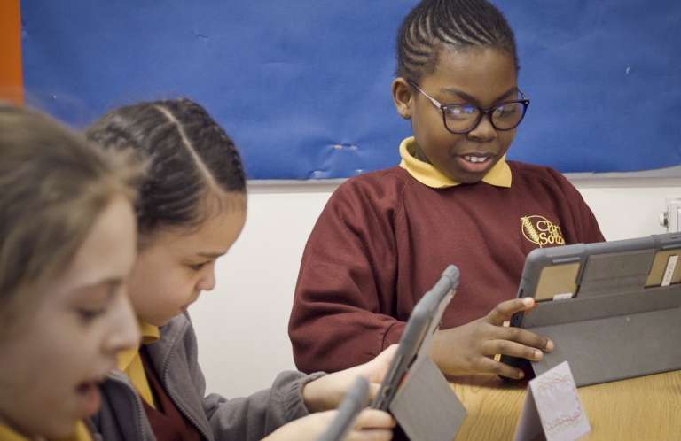 Three girls on computer tablets.
