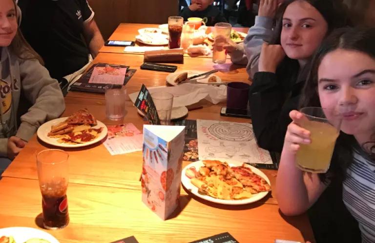 group of teenagers sitting around a table at a restaurant