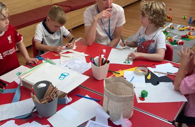 Children and adults sitting around a table drawing