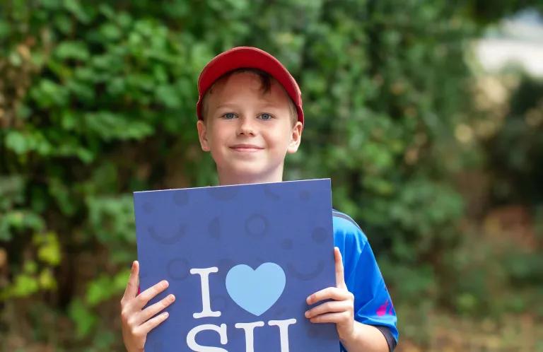 Child holding I love SU poster