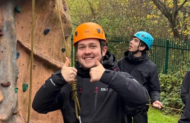 A young man next to a climbing wall