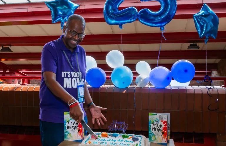 Wayne cuts the cake at our celebration of 25 years of It's Your Move