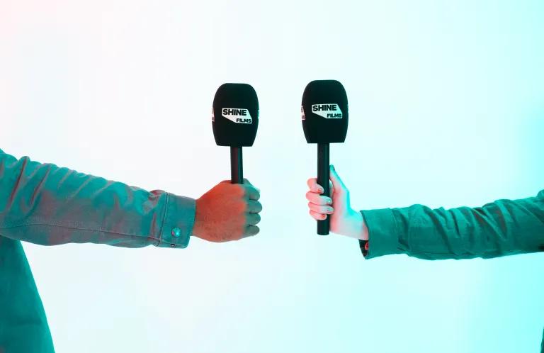 2 hands holding microphones