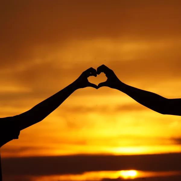 Child and adult in front of a sunset