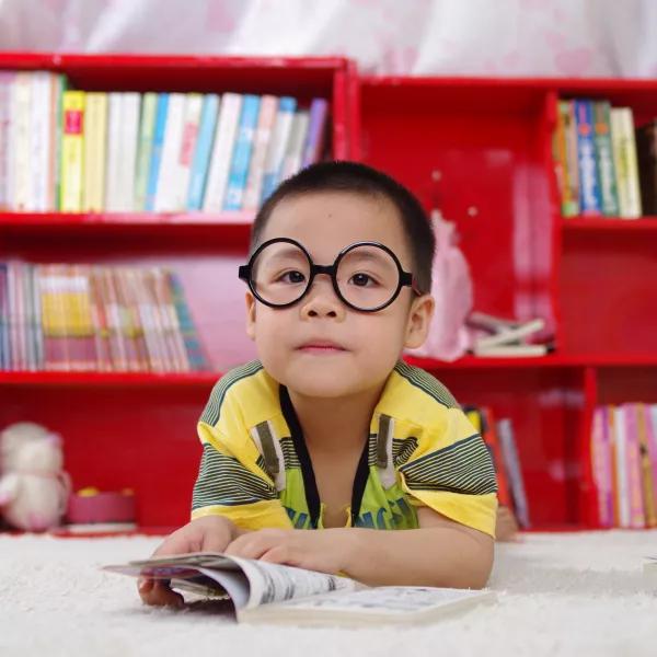 Boy wearing glasses reading book
