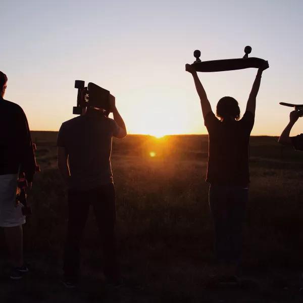 Holding up skateboards to the sunset