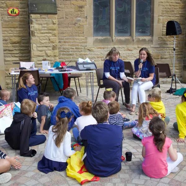 Group of children and adults listening to speaker