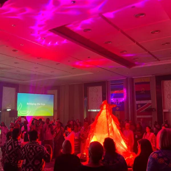global gathering - people dancing around indoor fire pit