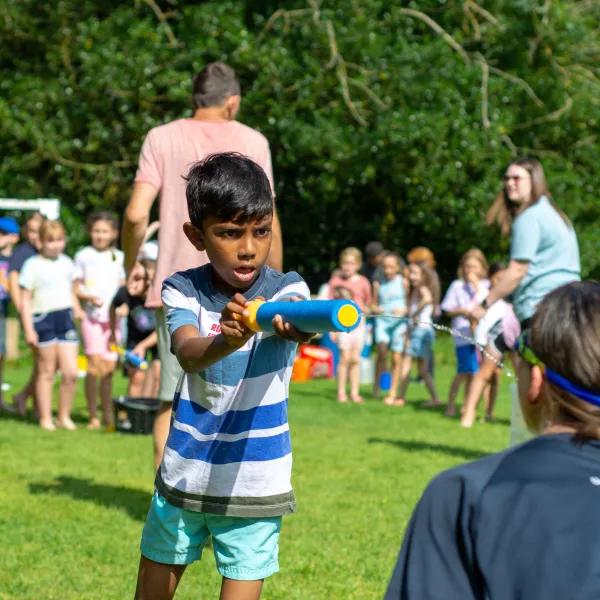A child squirting a water pistol at a leader's face