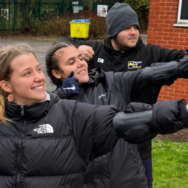 3 young people practise an archery pose