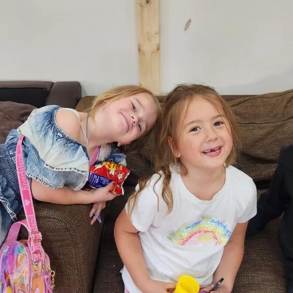 3 young children laughing on sofa
