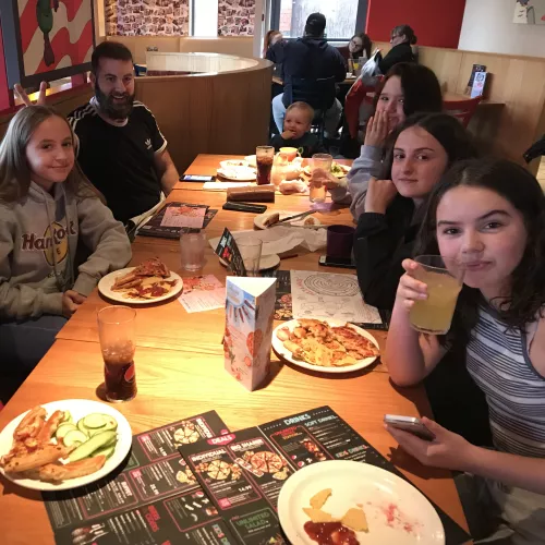 group of teenagers sat around a table at a restaurant