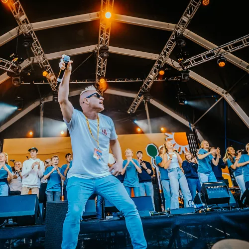 Chip K leads an energetic choir of children on a large stage