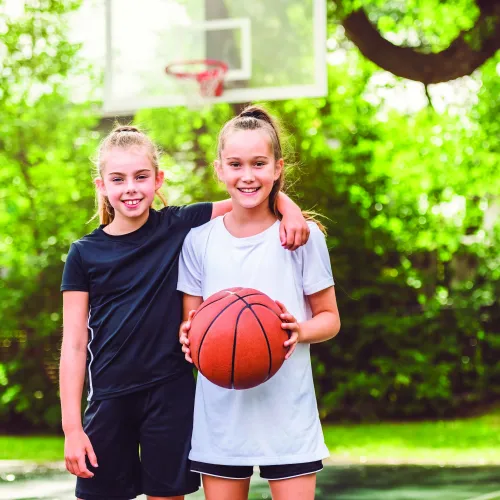 Two girls, one holding basketball