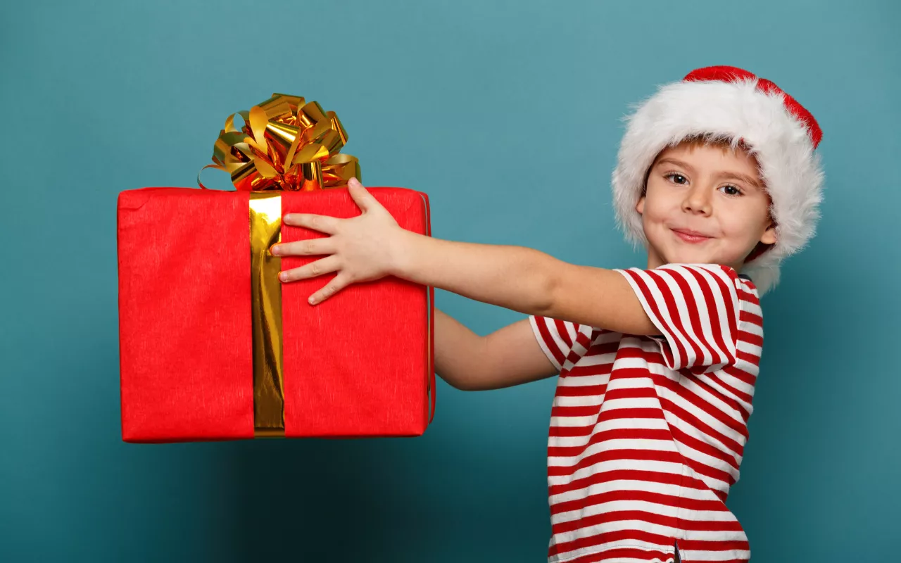 Young child in Christmas hat holding large gift